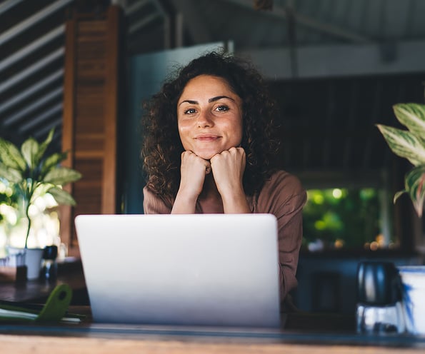 Photo of happy marketing manager looking at camera over her laptop