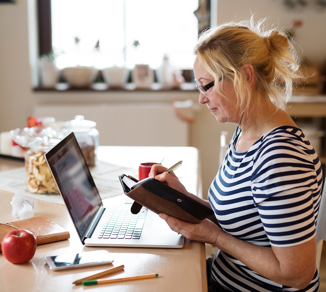 Photo of a woman at a desk checking her calendar